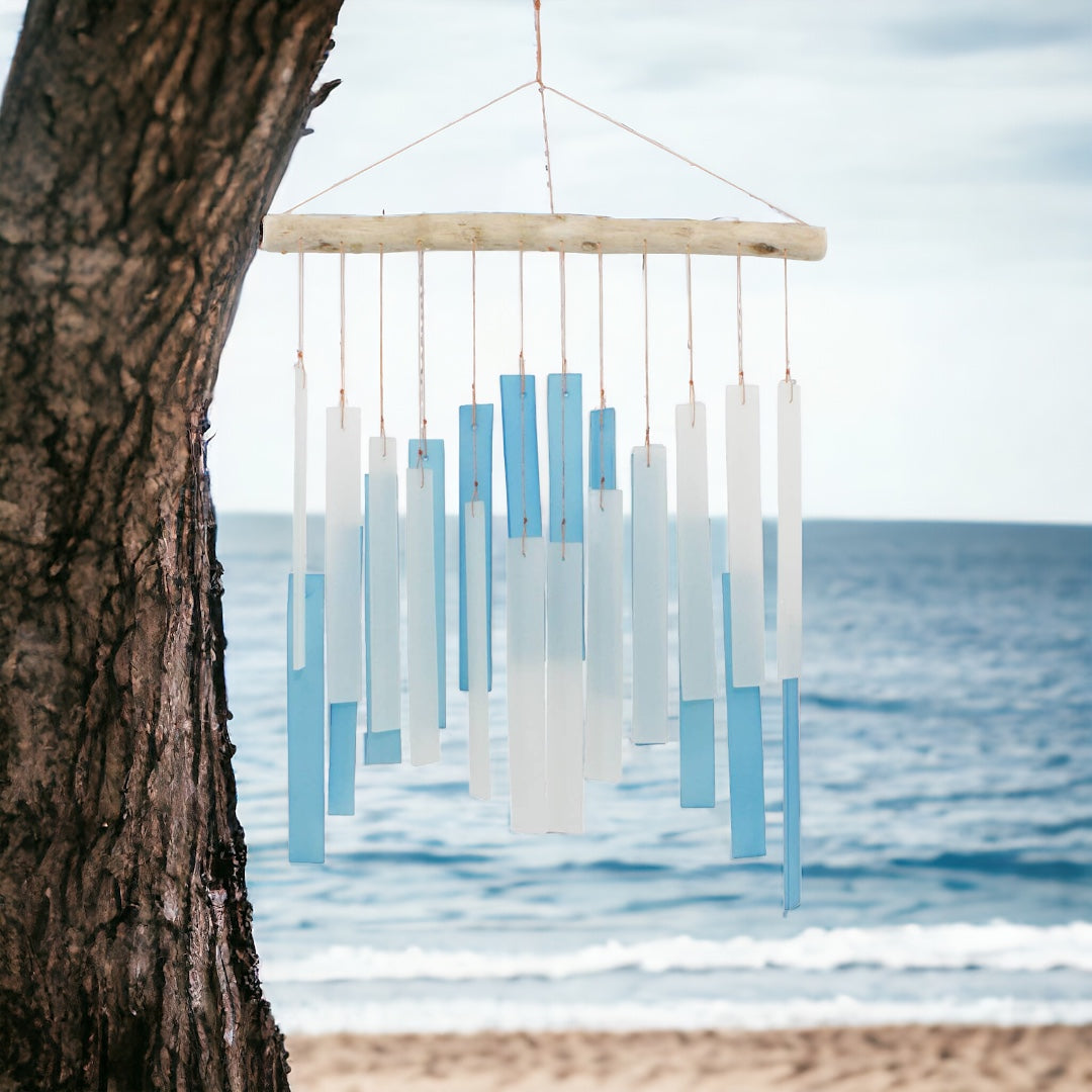 Light Blue and White Skyline Tumbled Glass Wind Chime, front view with beach background